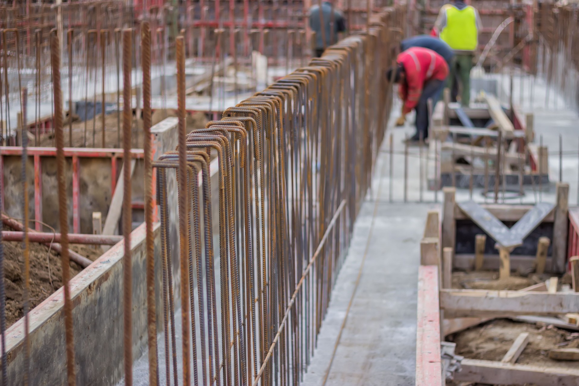 Blurred workers and steel reinforcement in foundation of  new bu